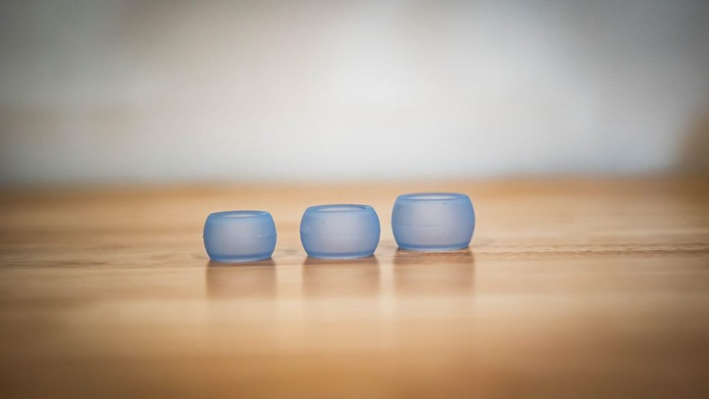 Three Ring Wrapper silicone ring covers in Azure, in small, medium and large, lined up on a wooden table